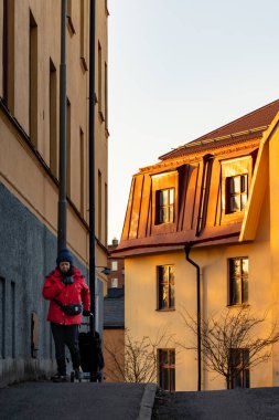 Stockholm, İsveç 20 Mart 2025 Bir kadın gün batımında orta sommarkransen bölgesinde bir evin önünden geçiyor..