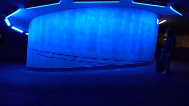 Stockholm, İsveç 'te bir adam mavi bir rampada tekerlekli bavulla yürüyor.. 