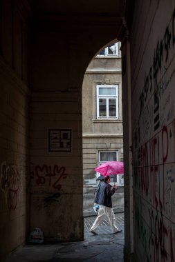 Zagreb, Hırvatistan 24 Mart 2025 Şemsiyeli bir kişi Yukarı Kasaba 'daki kemerli bir geçitten geçiyor.
