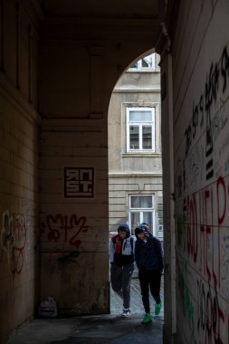 Zagreb, Hırvatistan 24 Mart 2025 Yukarı Kentte kemerli bir geçitten geçen iki genç adam.