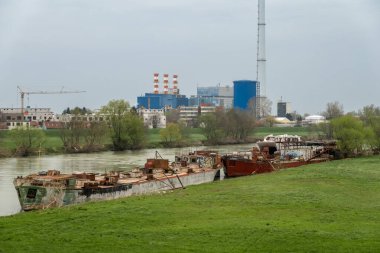 Zagreb, Hırvatistan 24 Mart 2025 Şehir merkezindeki Sava Nehri 'ne yanaşan eski nehir tekneleri ve bir ısıtma tesisi manzarası.