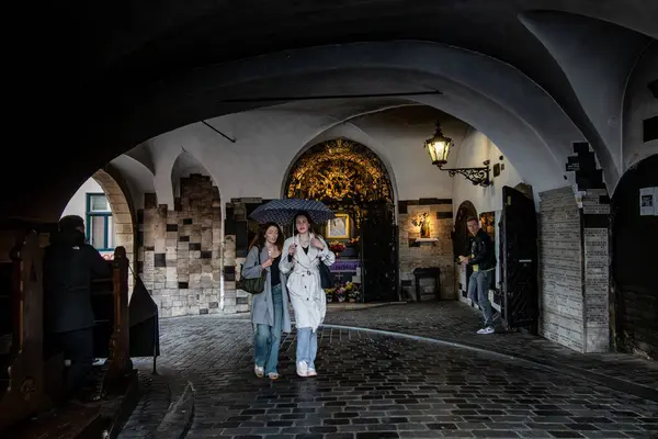 Zagreb, Hırvatistan 24 Mart 2025 Şemsiyeli iki genç kadın, ortaçağ Bakire Meryem türbesi olan Taş Kapı 'dan birlikte geçtiler.