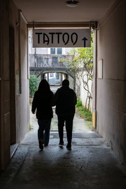 Zagreb, Hırvatistan 24 Mart 2025 İki kişi arka sokakta yürür ve dövme imzalar.