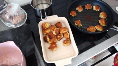 Stockholm, İsveç Bir aşçı Danimarka balık köftesi, ya da Fiskefrikadeller, bir indüksiyon sobası üzerinde yağ içinde.