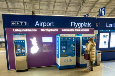 Helsinki, Finlandiya 10 Nisan 2025 Helsinki Vantaa Havaalanı tren istasyonundaki platform ve istasyon ve bilet alan bir kadın.