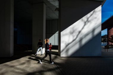 Stockholm, İsveç 15 Nisan 2025 Güneşli bir günde Arsta Köprüsü 'nün altından genç bir kadın koşucu geçiyor.