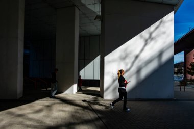 Stockholm, İsveç 15 Nisan 2025 Güneşli bir günde Arsta Köprüsü 'nün altından genç bir kadın koşucu geçiyor.