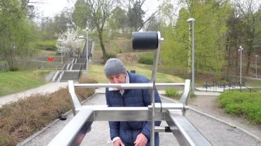 Stockholm, İsveç. Sokak kıyafetleri içinde bir adam parktaki açık hava spor salonunda çalışıyor.. 