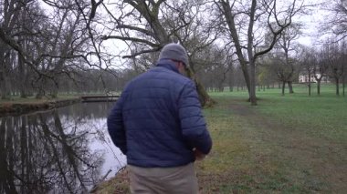 Stockholm, İsveç Bulutlu ve yağmurlu bir günde, baharda yaşlı meşe ağaçlarıyla ağaçlık bir parkta yürüyen bir adam.. 