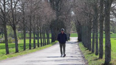 Eskilstuna, İsveç Baharda ağaçlık bir sokakta bir adam yürüyor. 