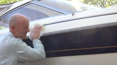 Stockholm, İsveç Teknesi 'nin fiberglas gövdesini balmumuyla cilalıyor. Bir tekne kulübünde tekne sezonu başlamadan önce..  