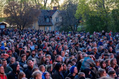 Stockholm, İsveç 30 Nisan 2025 'te kalabalık konuşmaları dinlemek ve Walpurgis gecesini kutlamak için halka açık bir parkta büyük bir şenlik ateşi seyretmek için toplandı..