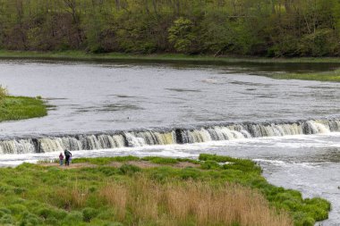 Kuldiga, Letonya 6 Mayıs 2025 Avrupa 'nın 249 metre çapındaki en geniş şelalesi olan Venta Rapids veya Kuldiga Şelalesi' nden yürüyen insanlar