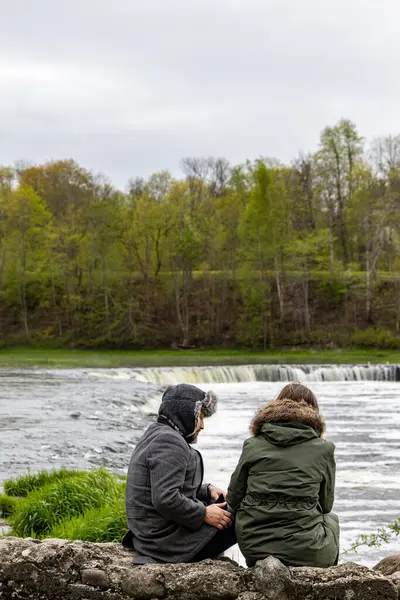 Kuldiga, Letonya 6 Mayıs 2025 Kuldiga şelalesinin yanında oturan bir erkek ve bir kadın veya Venta Rapids, Avrupa 'nın 249 metre çapındaki en geniş şelalesi..