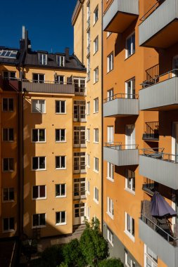 Stockholm, İsveç 16 Mayıs 2025 Svarvargatan 'ın Kungsholmen bölgesinde pencereleri ve balkonları olan bir apartman dairesinin turuncu ve siyah cephesi..