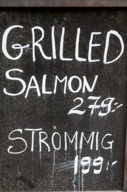 Stockholm, İsveç 18 Mayıs 2025 Restoran karatahta levhası ızgara somon ve kızarmış ringa veya stromming sunar..
