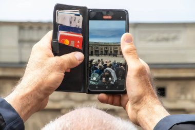Stockholm, İsveç 18 Mayıs 2025. Turistler Kraliyet Sarayı 'ndaki nöbetçi değişiminin fotoğrafını çekmek için akıllı telefonlarını kullanıyorlar..