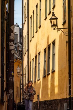 Stockholm, İsveç 18 Mayıs 2025 Genç bir kadın Gamla Stan veya Old Town 'da dar bir sokakta yürüyor.