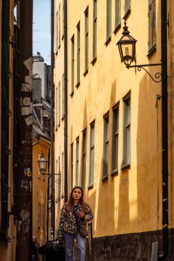 Stockholm, İsveç 18 Mayıs 2025 Genç bir kadın Gamla Stan veya Old Town 'da dar bir sokakta yürüyor.
