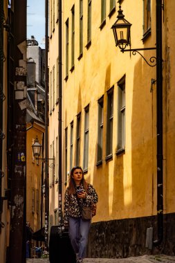 Stockholm, İsveç 18 Mayıs 2025 Genç bir kadın Gamla Stan veya Old Town 'da dar bir sokakta yürüyor.