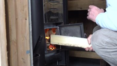 Stockholm, İsveç Bir adam sauna odun sobasını yakıyor.
