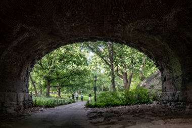 New York, New York, ABD 24 Mayıs 2025 Central Park 'ta kemerli bir geçitten geçen insanlar.