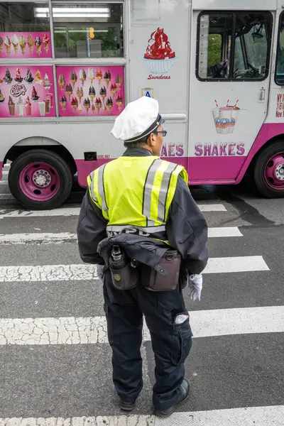 New York, New York, ABD Mayıs 2025 Central Park West 'te yaya geçidinde bir polis memuru ve bir dondurma kamyonu..