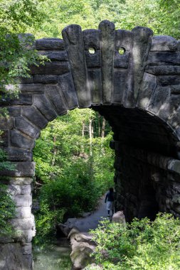 New York, New York, ABD 24 Mayıs 2025 Central Park 'taki Kuzey Ormanı' ndaki geçitte bir kemerin altında yürüyen insanlar.