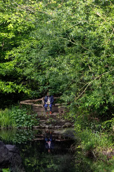 New York, New York, ABD 24 Mayıs 2025 Central Park 'taki Kuzey Ormanı' nda bir adam oturuyor..