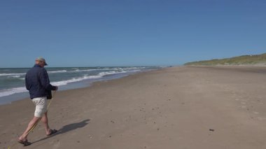 Hirtshals, Danimarka sahilde tasmalı bir köpekle yürüyen bir adam.. 