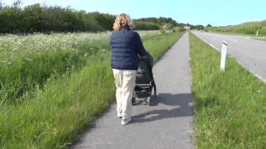 Hirtshals, Danimarka Bir büyükanne bisiklet yolunda bir bebek arabasıyla yürür. 