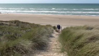 Hirtshals, Danimarka Bir adam sahil kum tepelerinde bir köpekle yürüyor. 
