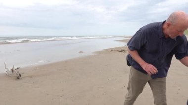 Hirtshals, Danimarka 'da bir adam soğuk ve dalgalı bir Kuzey Denizi sahilinde yüzmek için elbiselerini çıkarıyor..  