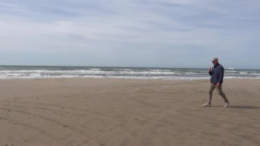 Hirtshals, Danimarka Kuzey Denizi sahilinde bir adam dondurma ile yürüyor.. 