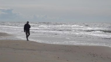 Hirtshals, Danimarka Kuzey Denizi sahilinde bir adam dondurma ile yürüyor.. 