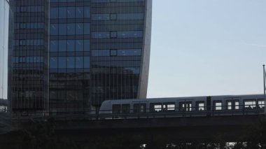 Kopenhag, Danimarka M1 hattında yükseltilmiş bir metro treni Orestad bölgesindeki modern binalardan geçiyor..  