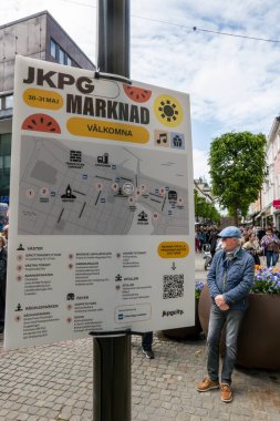 Jnkping, İsveç. Şehir merkezindeki kalabalık kasabada bir adam Jonkoping market günüyle ilgili İsveççe bir levhanın yanında duruyor..