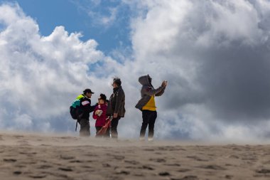 Skagen, Danimarka 2 Haziran 2025 Rabjerg Mil 'in rüzgârlı kum tepelerinde yürüyen insanlar.