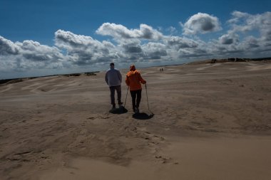 Skagen, Danimarka 2 Haziran 2025 Rabjerg Mil 'in rüzgârlı kum tepelerinde yürüyen insanlar.