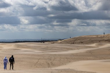 Skagen, Danimarka 2 Haziran 2025 Rabjerg Mil 'in rüzgârlı kum tepelerinde yürüyen insanlar.