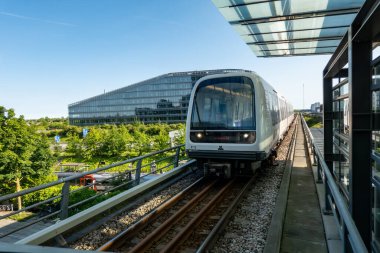 Kopenhag, Danimarka 12 Haziran 2025 M1 hattındaki yüksek bir metro treni Orestad bölgesindeki modern binalardan geçiyor..