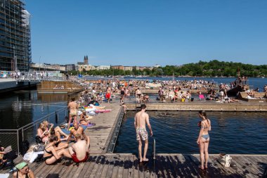 Stockholm, İsveç 15 Haziran 2025 İnsanlar Liljeholmen bölgesinde yeni bir halka açık ve serbest yüzme platformunda yüzüyor ve güneşleniyor.