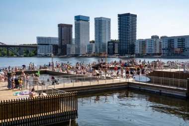 Stockholm, İsveç 15 Haziran 2025 İnsanlar Liljeholmen bölgesinde yeni bir halka açık ve serbest yüzme platformunda yüzüyor ve güneşleniyor.
