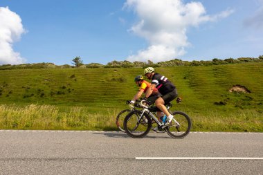 Mors, Danimarkalı bisikletçiler yemyeşil manzara ve otlar arasındaki yolda Kuzey Jutland Limfjord 'daki Mors adasında.