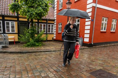Ribe, Danimarka 10 Haziran 2025 Şemsiyeyle yürüyen insanlar Eski şehrin parke taşlı sokaklarında.