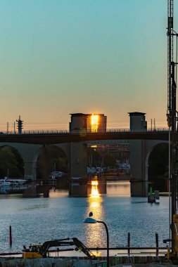 Stockholm, İsveç Arsta Köprüsü 'nün gün doğumu manzarası ve sokak lambasının üzerindeki bir martı..