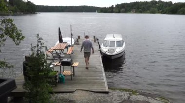Stockholm, İsveç 'te bir adam Malaren Gölü' ndeki bir kulübede ve rıhtımda bir tekne boşaltıyor.. 