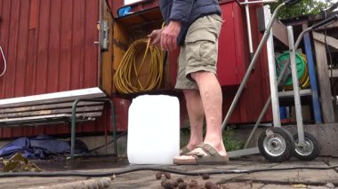 Stockholm, İsveç 'te bir adam göl kıyısındaki bir rıhtımda plastik bir kabı içilebilir suyla dolduruyor..