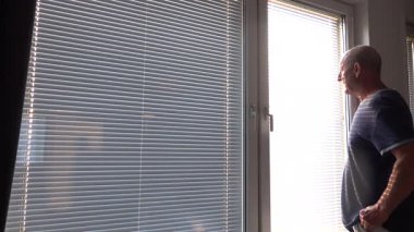 Stockholm, İsveç. Bir adam sabah yatak odasında pencere perdelerini açar.. 