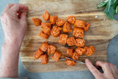 Stockholm, İsveç 'te bir el, ahşap bir kesme tahtasının üzerinde sucuk parçalarına ayırır..